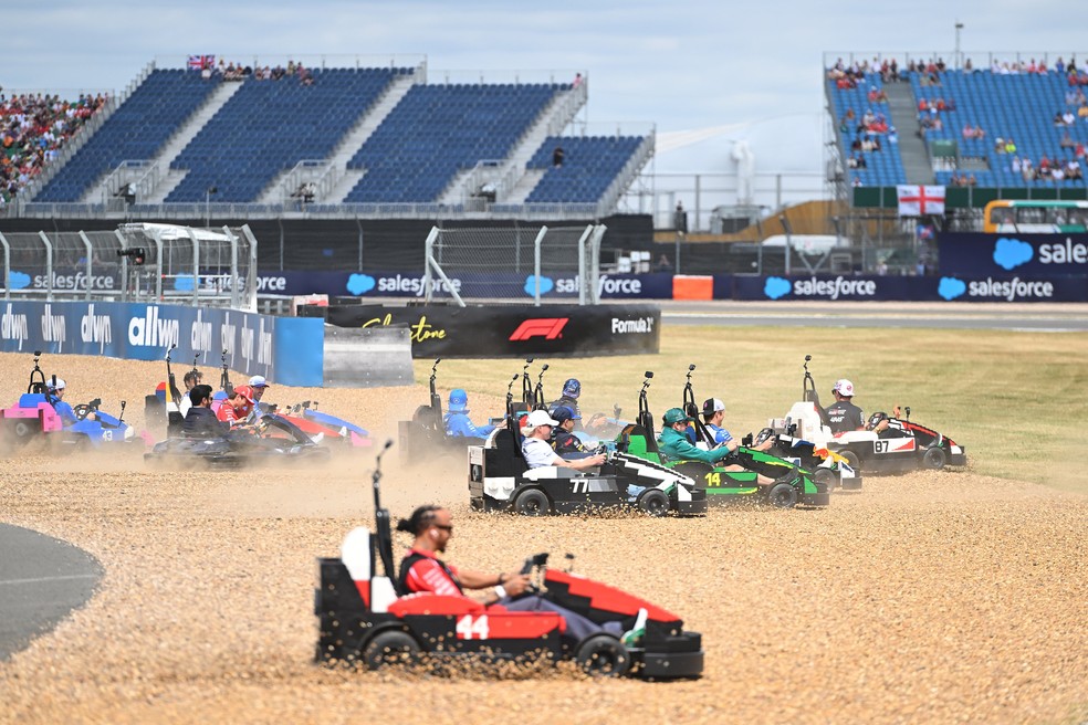 Pilotos da F1 passam com karts pela brita — corrida de Lego