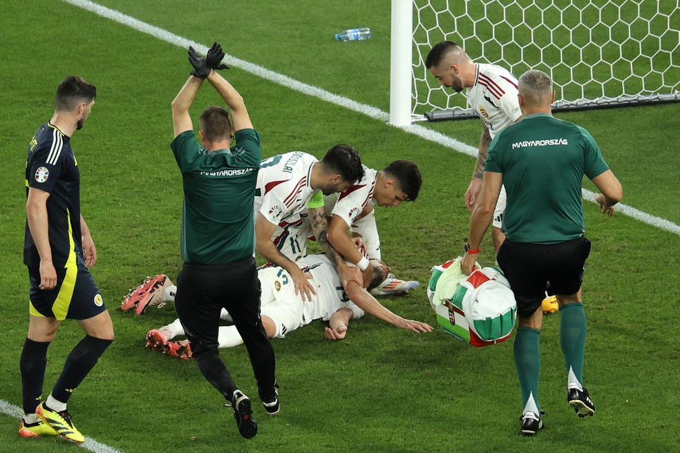 Varga, da Hungria, cai desacordado após choque de cabeça em jogo com Escócia, na Eurocopa, e médico faz sinal de concussão — Foto: Ronald Wittek/EFE