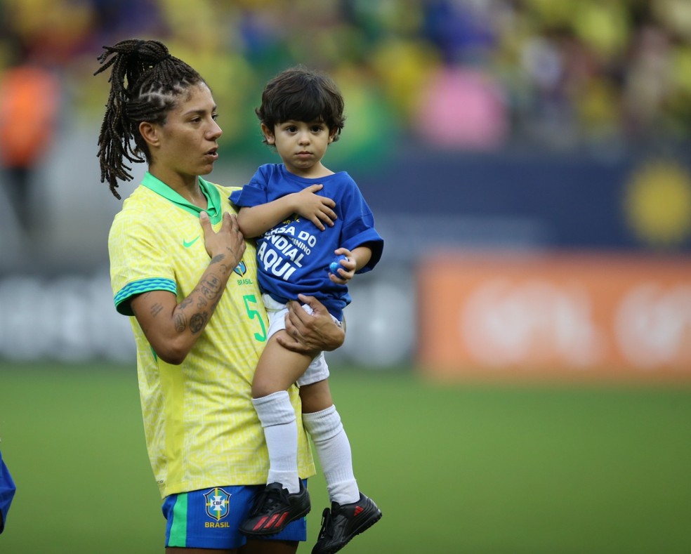 Cristiane segurando o filho Bento, de 3 anos, em Brasil x Jamaica — Foto: Marlon Costa/Pernambuco Press