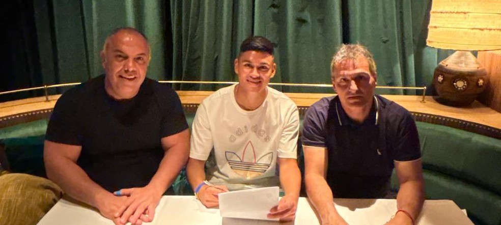 Carlos Alcaraz assina contrato com o Flamengo, ao lado de Marcos Braz e Bruno Spindel em Londres — Foto: Divulgação