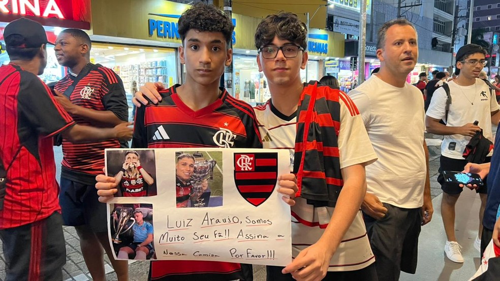Torcedores levam cartaz para Luiz Araújo na chegada do Flamengo a Santos.