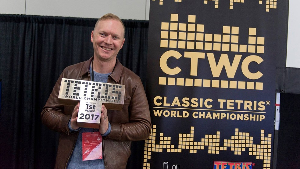 Jonas Neubauer segurando o troféu do Classic Tetris World Championship de 2017, o sétimo e último conquistado pelo norte-americano antes de morrer aos 39 anos, em 2021 — Foto: Divulgação/Classic Tetris World Championship