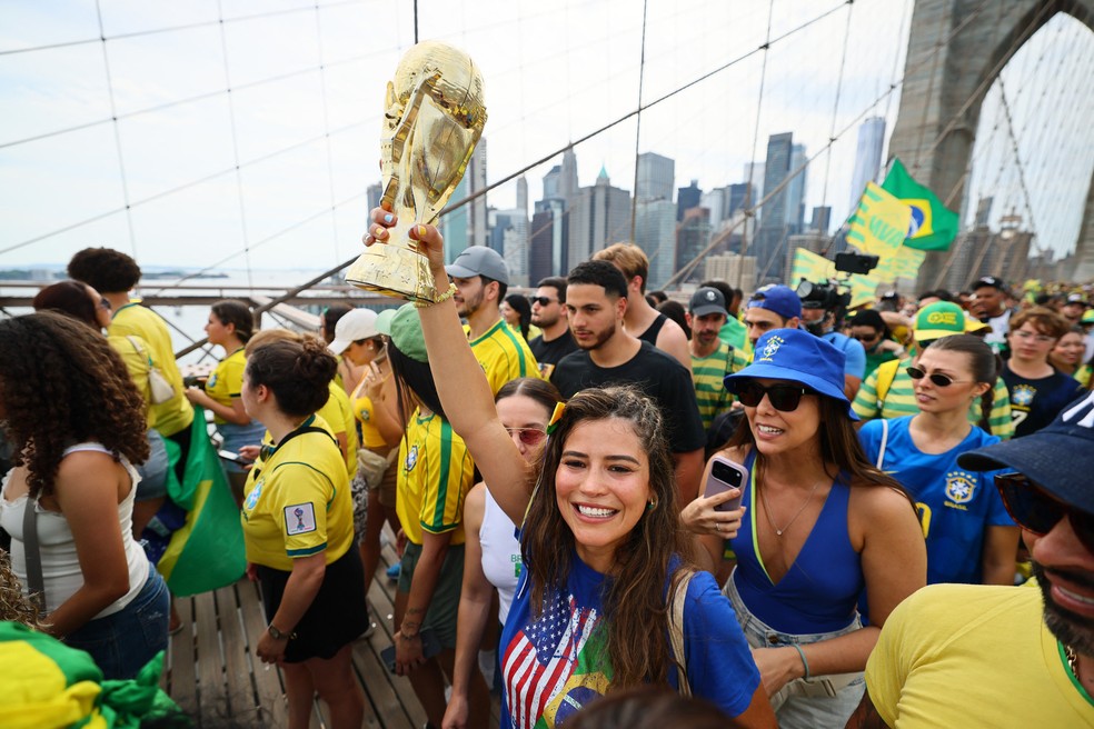 Torcedora exibe troféu durante ato na Ponte do Brooklyn