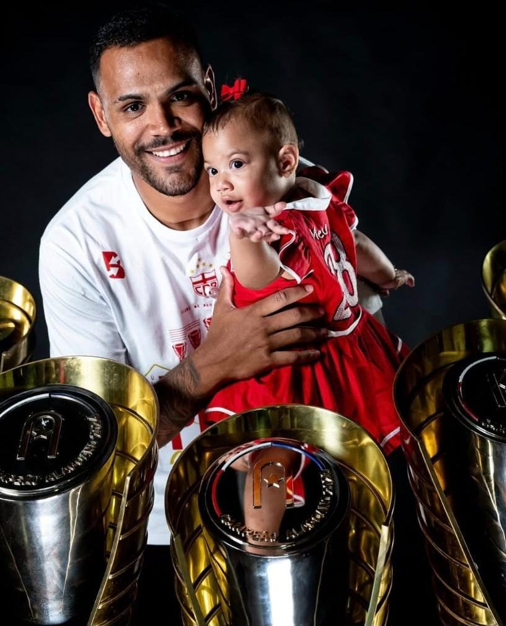Mikael posa com a filha e as cinco taças do Alagoano do CRB — Foto: Francisco Cedrim/ASCOM CRB