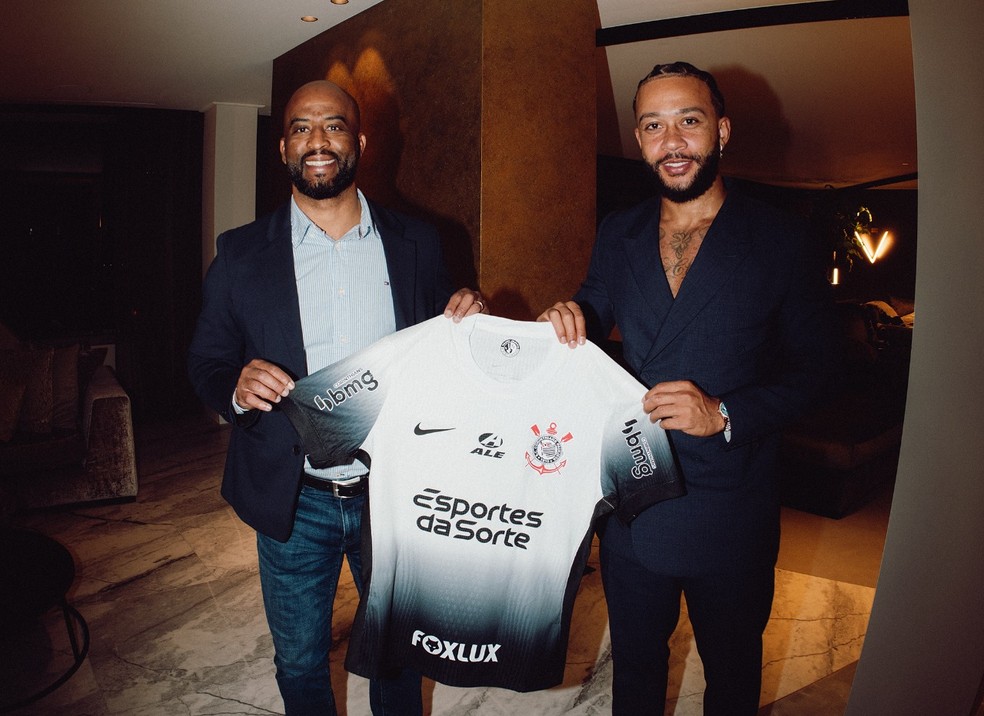 Memphis Depay posa com o diretor Fabinho Soldado e a camisa do Corinthians — Foto: Divulgação