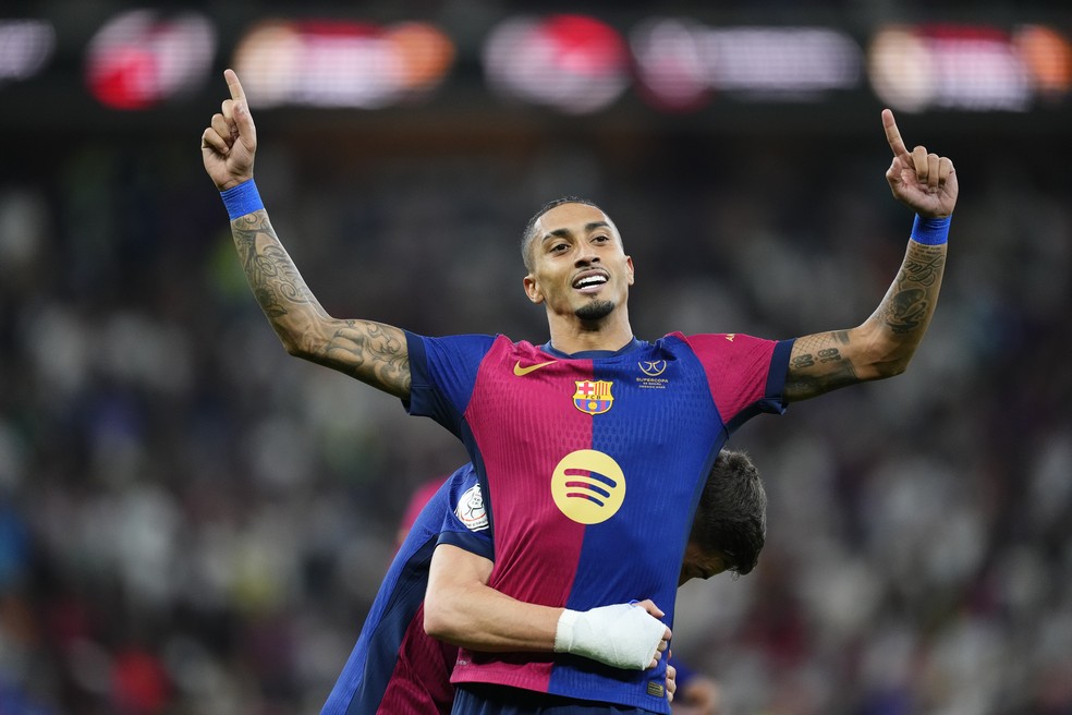 Raphinha comemora um de seus gols contra o Real Madrid no título do Barcelona — Foto: Jose Breton/Pics Action/NurPhoto via Getty Images)