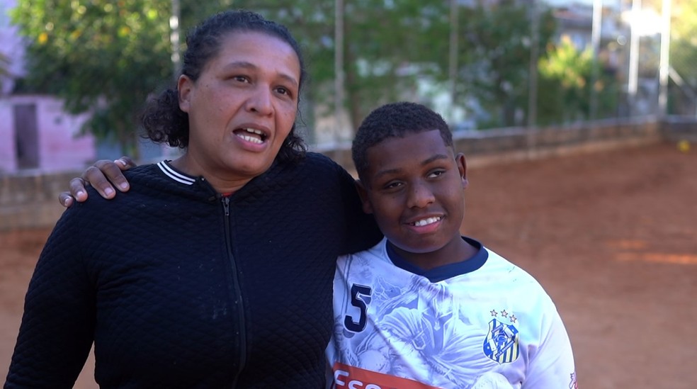 João com a mãe no campo de terra onde joga futebol — Foto: Alex Cardim/ EPTV