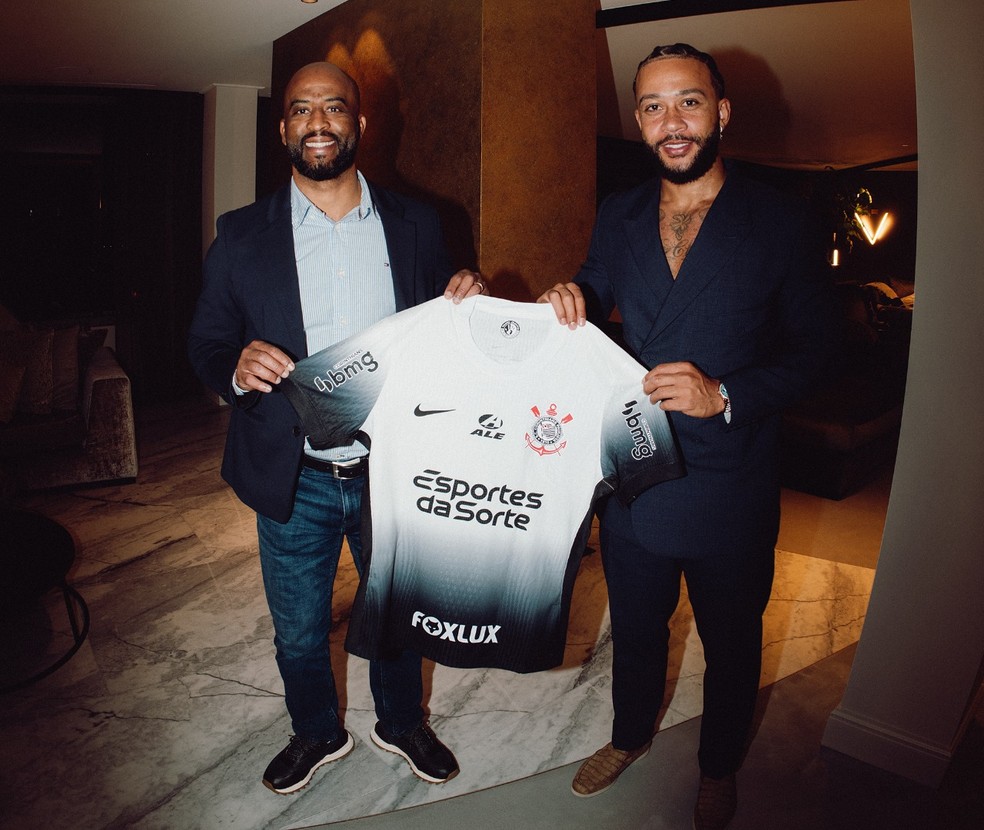 Memphis Depay posa com o diretor Fabinho Soldado e a camisa do Corinthians — Foto: Divulgação