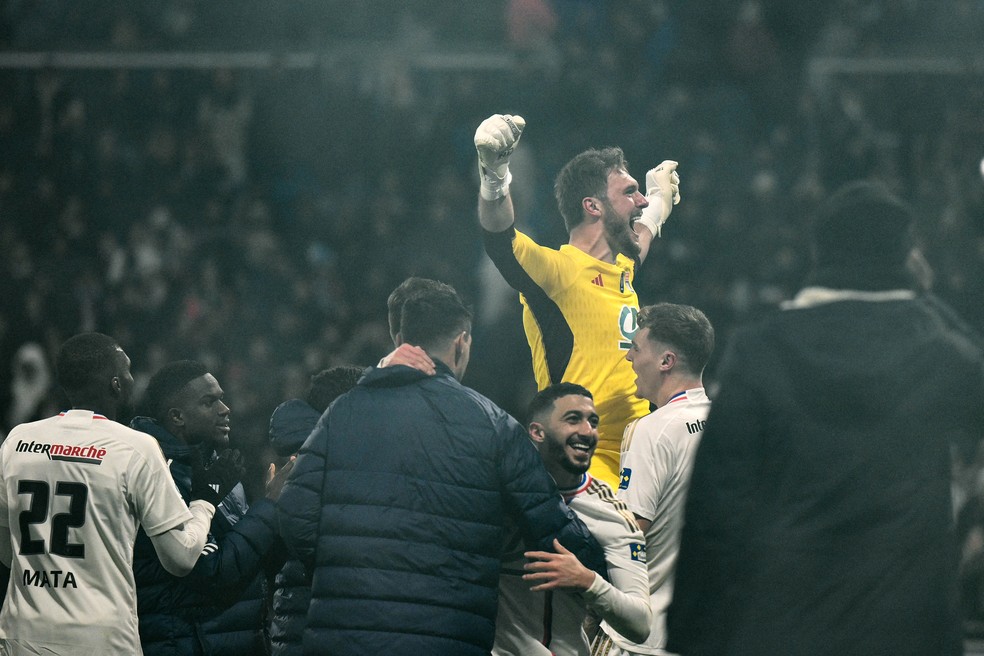 Lucas Perri é celebrado pelos companheiros após ser herói nos pênaltis na classificação do Lyon contra o Strasbourg na Copa da França — Foto: Jeff Pachoud/AFP