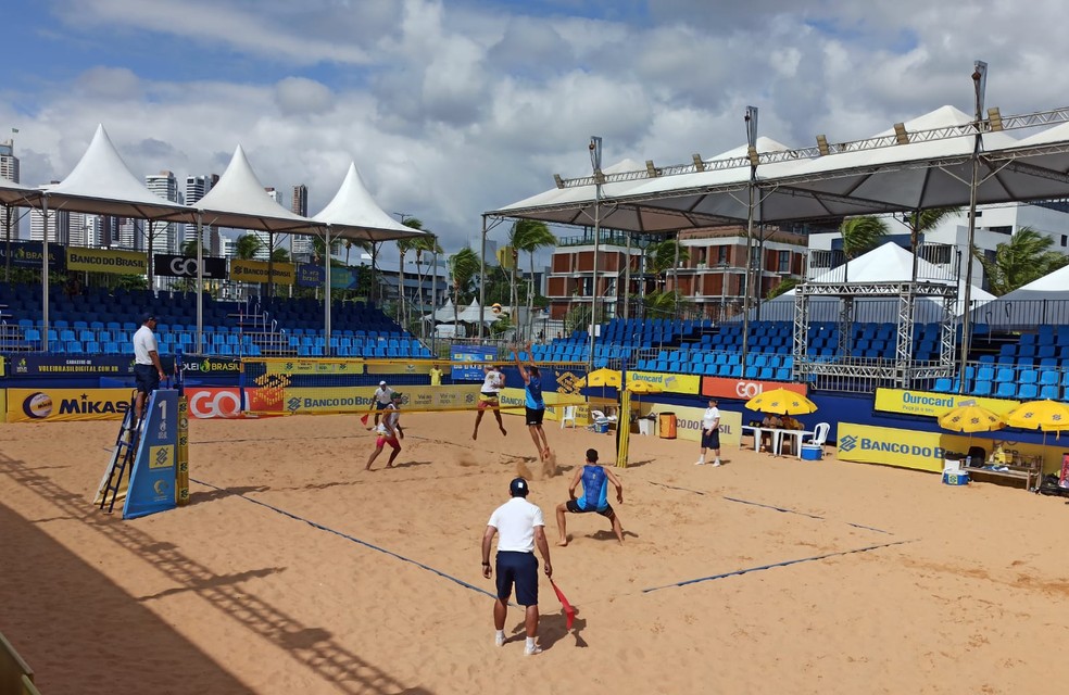 Imagem de pessoas jogando vôlei no fim de tarde.