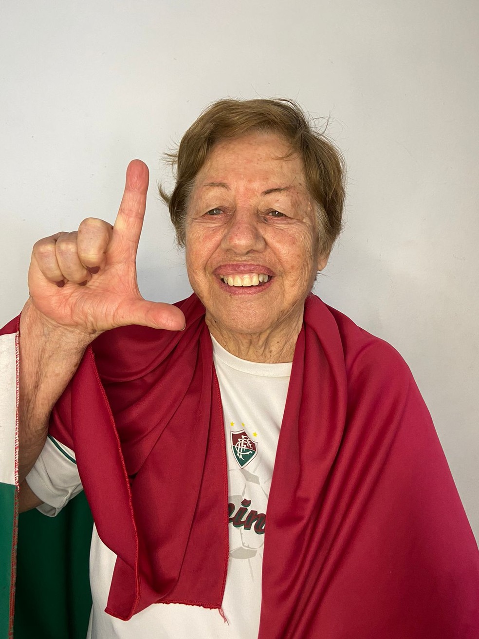 Dona Nizete com camisa e bandeira do Fluminense e fazendo o L do Cano — Foto: Arquivo Pessoal