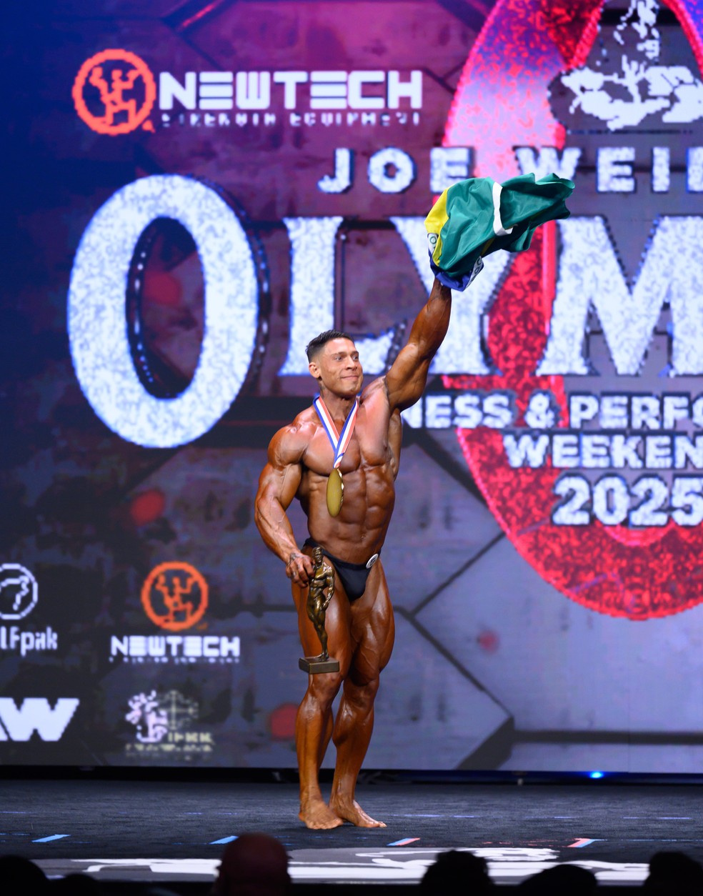 Ramon Dino com a bandeira e o troféu após o título do Mr. Olympia 2025 — Foto: Divulgação/Integralmédica