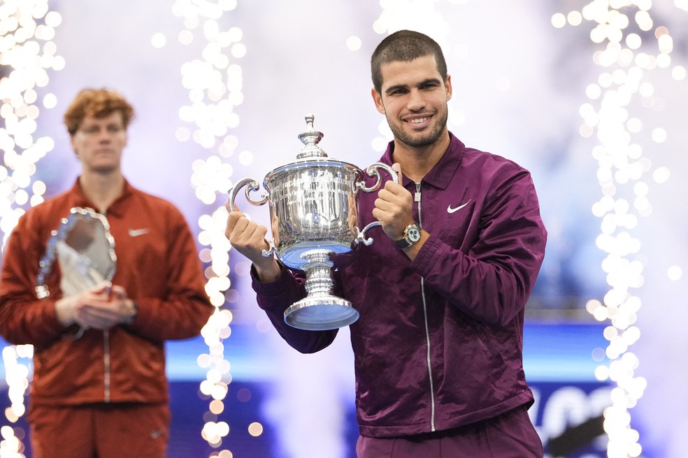 Carlos Alcaraz mostra a taça do US Open observado pelo vice-campeão Sinner — Foto: Robert Deutsch-Imagn Images