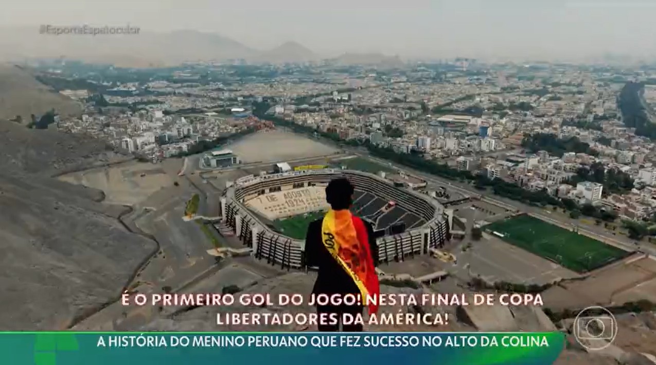 Imagem de Cliver Huamán Sánchez narrando de uma montanha ao lado do Estádio Monumental, com uma câmera filmando sua atuação.