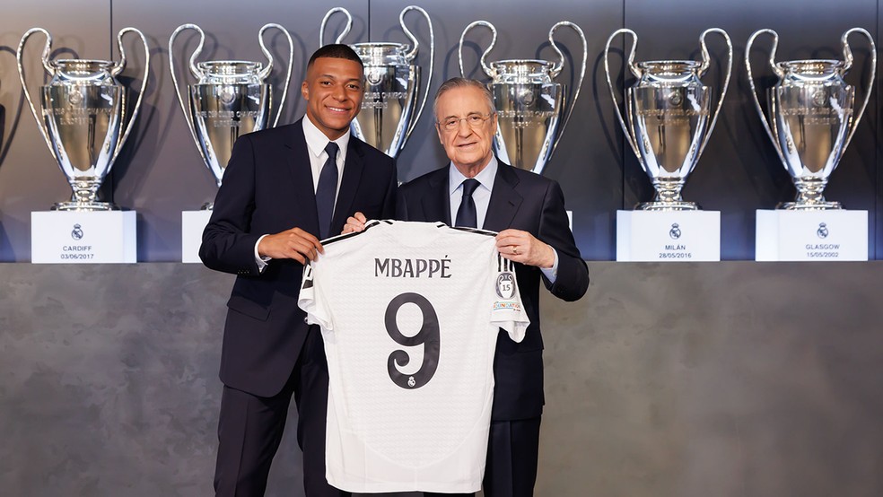 Mbapp com a camisa 9 do Real Madrid ao lado do presidente Florentino Prez e com trofus da Champions League no fundo  Foto: Pedro Castillo / Real Madrid