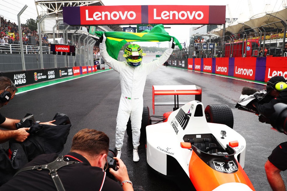 Lewis Hamilton com a bandeira do Brasil, ao lado de icônica McLaren de Senna, depois de voltas em homenagem no Autódromo de Interlagos — Foto: Peter Fox/Formula 1 via Getty Images