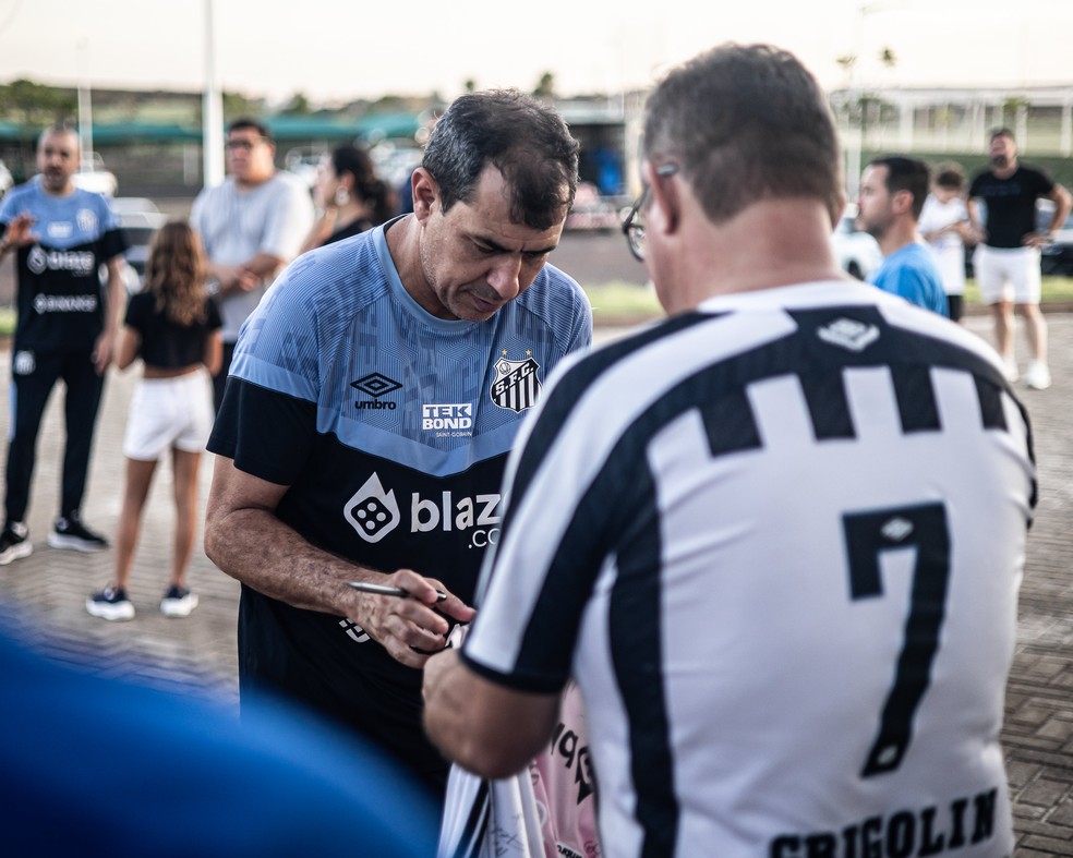 Fábio Carille dá autógrafo em camisa de torcedor do Santos — Foto: Raul Baretta/Santos