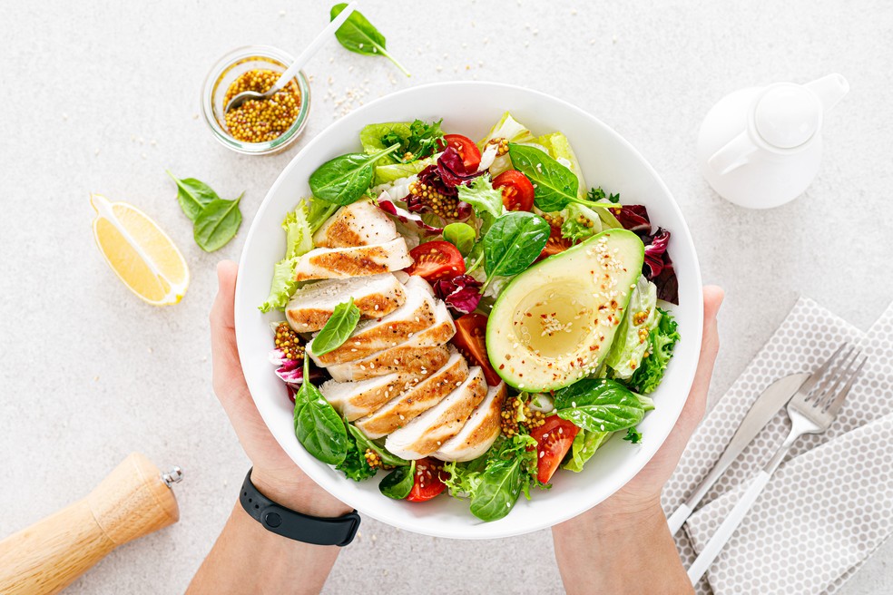 Frango e salada de tomate, abacate, alface e espinafre — Foto: iStock