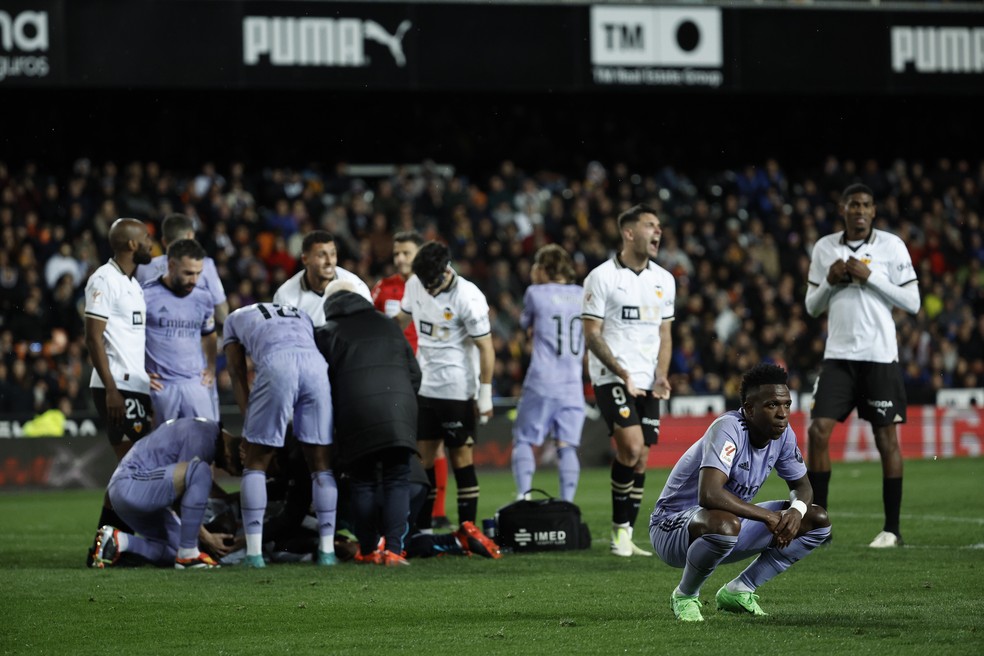 Vinicius Junior agachado e de costas enquanto Diakhaby recebe atendimento por lesão no joelho em Valencia x Real Madrid pela La Liga — Foto: EFE / Biel Aliño