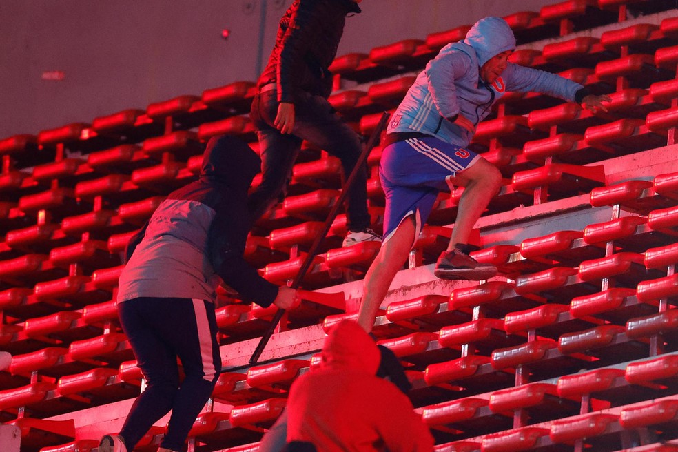 Torcedor da LA U tenta fugir de torcedores do Independiente &mdash; Foto: EFE/ Juan Ignacio Roncoroni