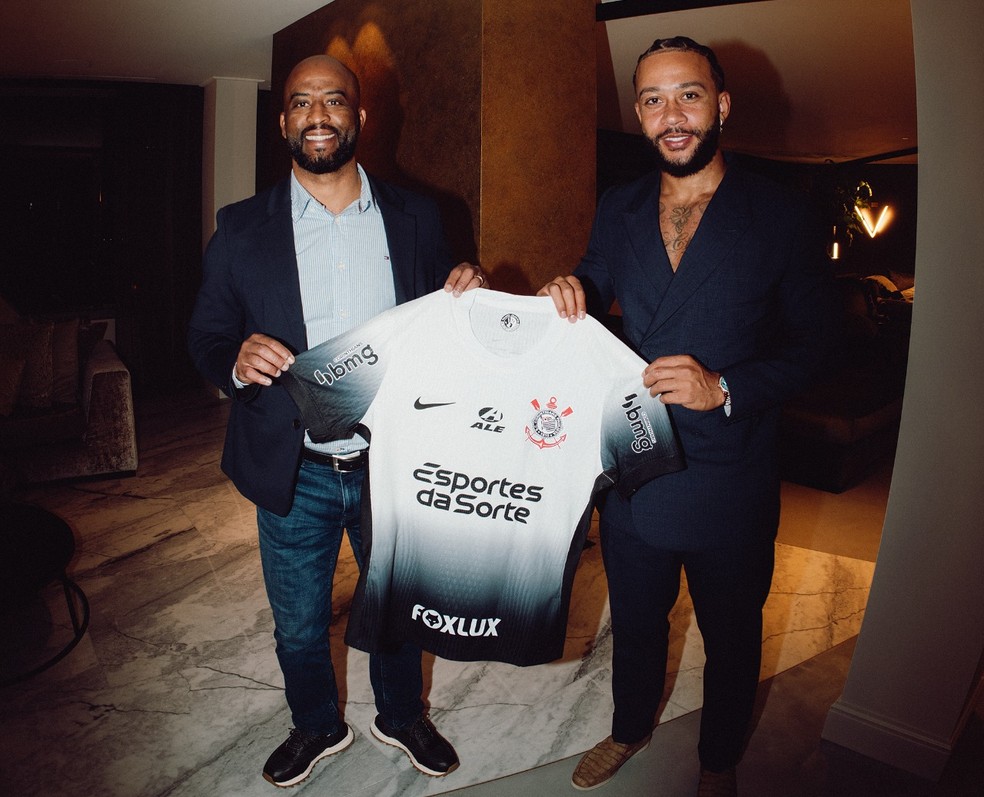 Memphis Depay posa com o diretor Fabinho Soldado e a camisa do Corinthians — Foto: Divulgação