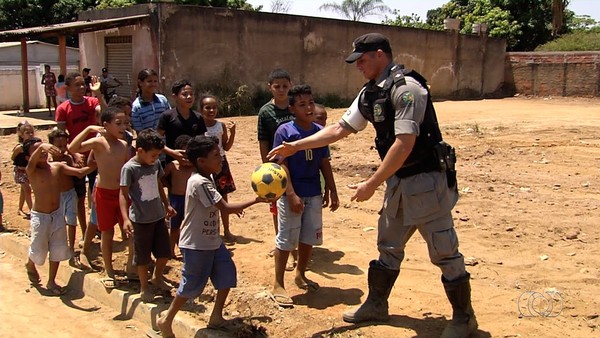 Policiais aceitam convite de crianças e jogam bola na rua durante