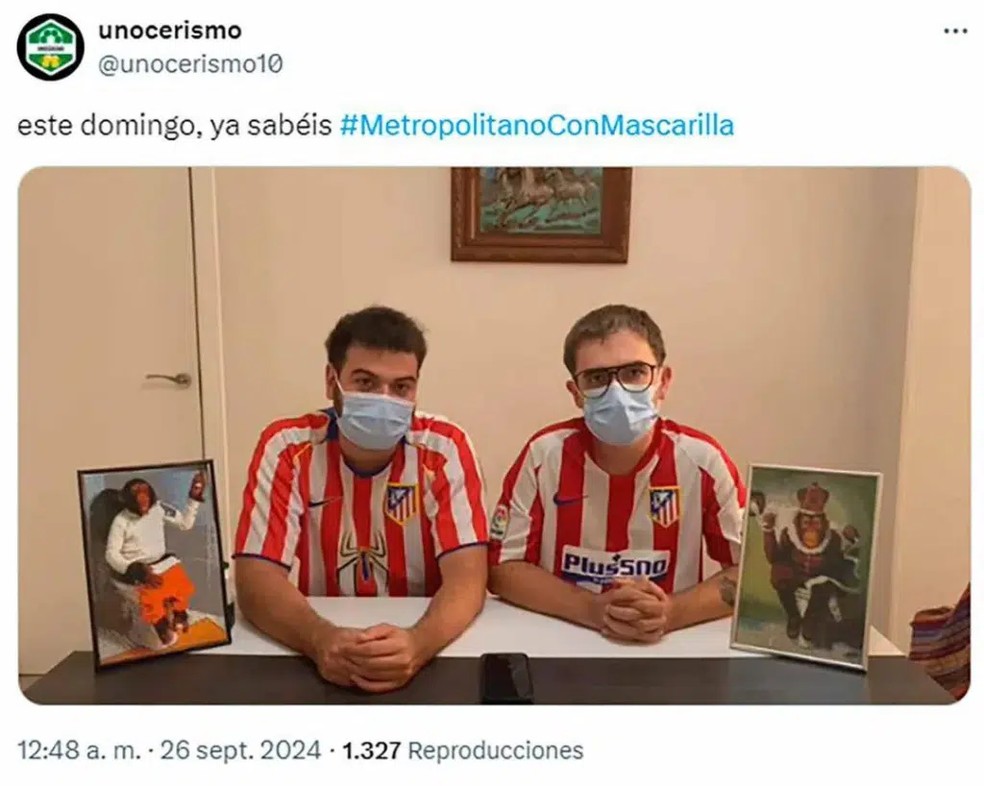 Dois torcedores do Atlético de Madrid com máscaras e quadros de macacos