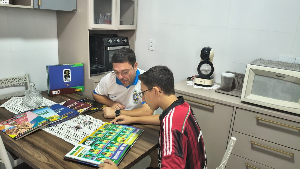 Pai e filho curtem a coleção de figurinhas mesmo após as chuvas