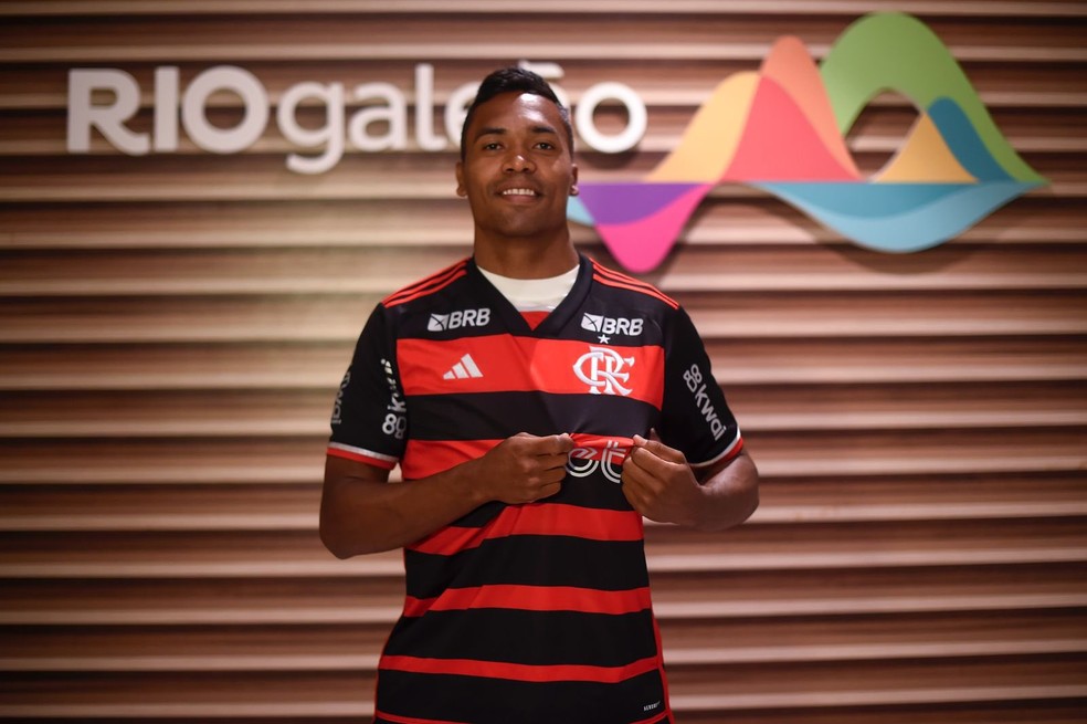 Alex Sandro veste a camisa do Flamengo na chegada ao Rio