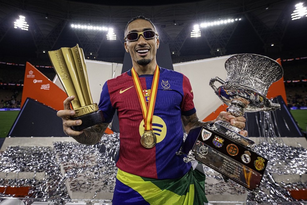 Raphinha exibe os troféus de MVP e de campeão da Supercopa da Espanha — Foto: Barcelona/Divulgação
