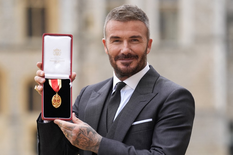 David Beckham recebendo título de cavaleiro das mãos do Rei Charles em cerimônia.