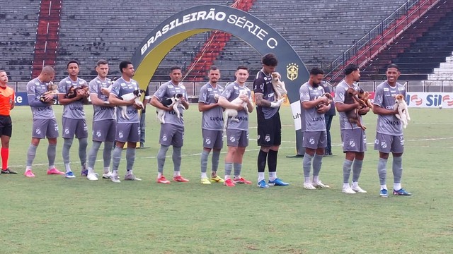 Jogadores da Inter de Limeira com cães para adoção antes de jogo da Série C