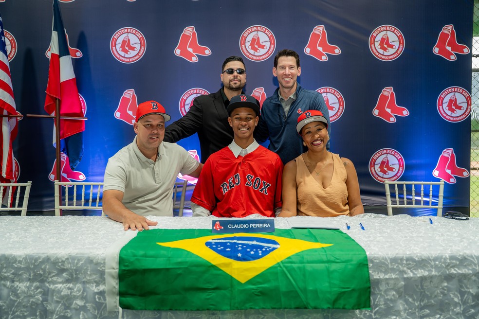 Cláudio Pereira assinou contrato de sete anos com o Boston Red Sox, da MLB. Na foto, está ao lado dos pais, do seu empresário Giovanny Cordero e do diretor-chefe do Red Sox, Craig Breslow — Foto: Divulgação/Red Sox