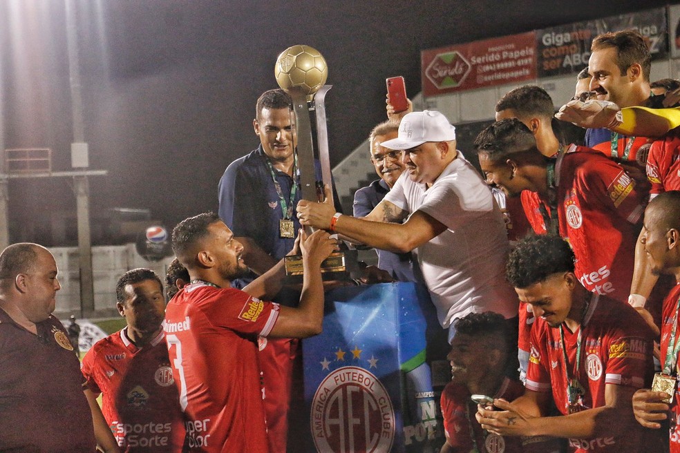 Souza entrega a taça de campeão estadual ao capitão Jean Pierre — Foto: Canindé Pereira/América FC