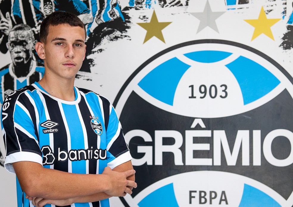 Pedro Vitor posando ao lado do escudo do Grêmio, no CT do Tricolor — Foto: Samy Oliveira / Serra Branca