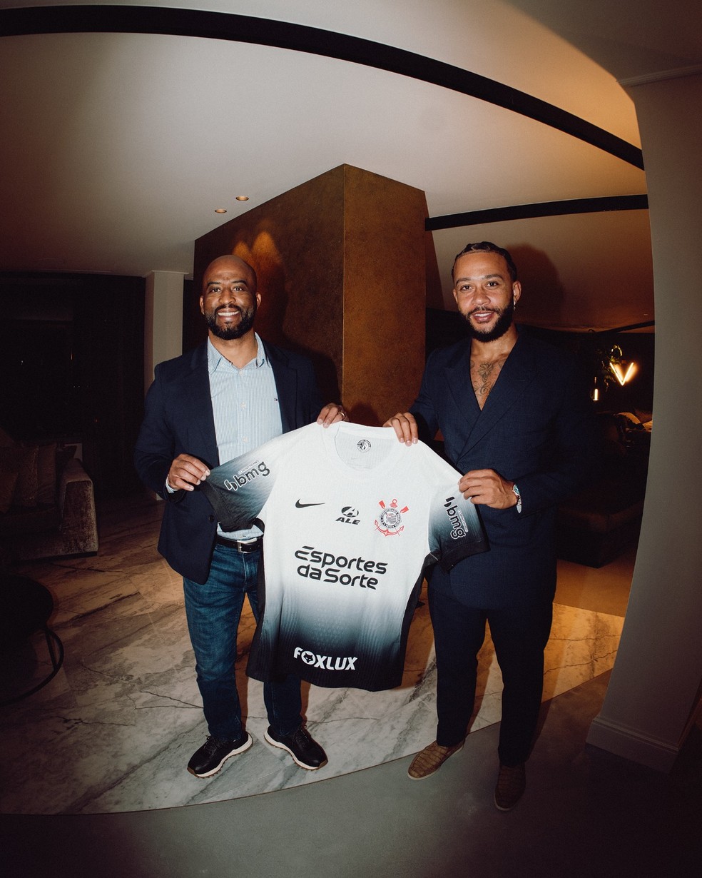 Memphis Depay posa com o diretor Fabinho Soldado e a camisa do Corinthians — Foto: Divulgação